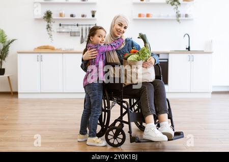 Mère en fauteuil roulant avec fille tenant un sac en papier avec des légumes frais Banque D'Images