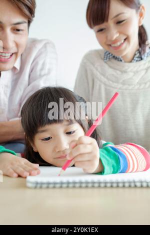 Couple souriant regardant leur fille dessiner un tableau Banque D'Images