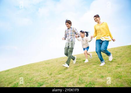 Famille japonaise courant sur la colline main dans la main Banque D'Images