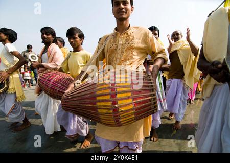 Percussionnistes jouant de leur tambour lors d'une cérémonie sur la plage du fleuve Ganga pendant le mela de Gangasagar au Bengale occidental, en Inde. Banque D'Images