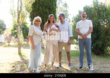 Une famille heureuse est debout ensemble dans le parc, célébrant l'arrivée de leur nouveau-né Banque D'Images