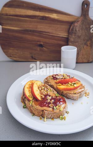 Beurre d'arachide et confiture de confiture avec pêche et noix, fond de cuisine. Concept de petit déjeuner végétalien. Banque D'Images