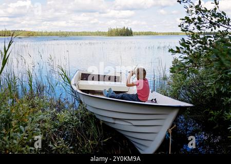 Enfants, jouer sur un bateau dans une rivière, l'été, regarder la nature avec des jumelles, temps ensoleillé l'été Banque D'Images