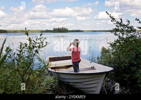 Enfants, jouer sur un bateau dans une rivière, l'été, regarder la nature avec des jumelles, temps ensoleillé l'été Banque D'Images