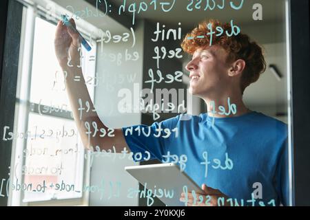Homme écrivant le code informatique sur le mur de verre Banque D'Images