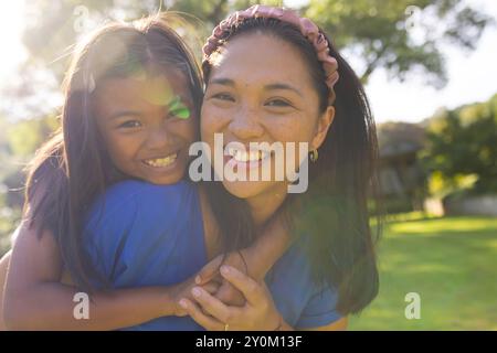 Mère et fille souriantes profitant du temps en plein air ensemble dans le parc ensoleillé Banque D'Images