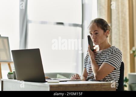 Une femme atteinte de vitiligo converse soigneusement tout en étant assise à son bureau. Banque D'Images