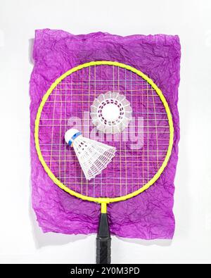 Raquette de badminton et deux volants placés sur du papier violet froissé, mettant en valeur une configuration vibrante et ludique. Parfait pour promouvoir des accessoires de sport, Banque D'Images