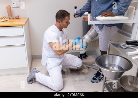 Technicien ajustant la jambe prothétique pour le patient dans le laboratoire médical, assurant un ajustement approprié Banque D'Images