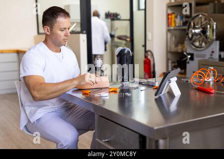 Technicien en laboratoire prothétique travaillant sur un membre artificiel avec des outils et des comprimés Banque D'Images