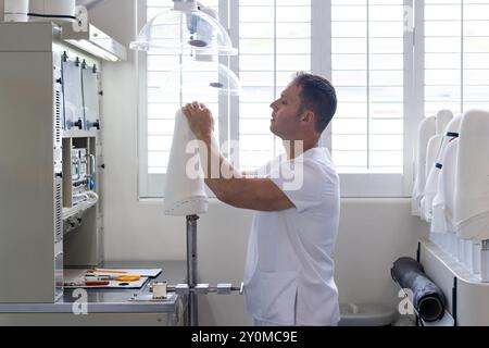 Technicien en laboratoire prothétique ajustant l'équipement pour la création de membres artificiels Banque D'Images