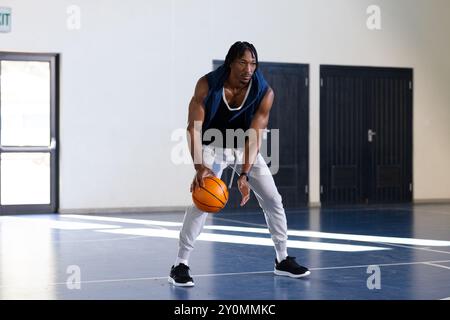 Dribble basket-ball sur terrain couvert, homme afro-américain pratiquant ses compétences Banque D'Images