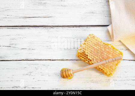 Morceau de miel frais biologique en nid d'abeille avec une trempette sur fond rustique, nourriture saine Banque D'Images