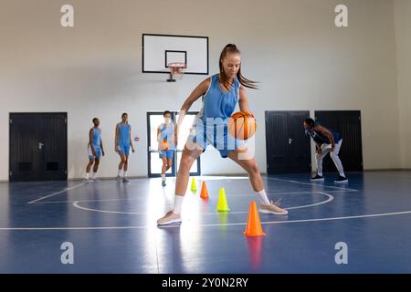 Dribble basket-ball autour des cônes, entraînement d'athlète féminin dans la salle de gym intérieure Banque D'Images