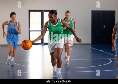 Jouer au basket-ball, les femmes dribbles et courir sur un terrain couvert pendant le match Banque D'Images