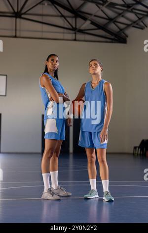 Jouant au basket-ball, deux athlètes féminines debout sur un terrain couvert en uniforme Banque D'Images