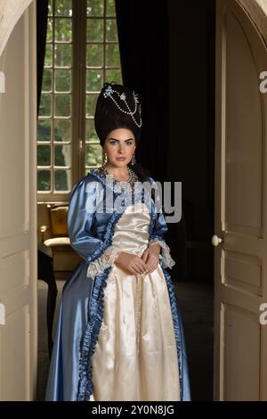 Belle jeune femme habillée dans le style rococo reine Marie Antoinette et portant une perruque authentique posant dans un intérieur de château français Banque D'Images