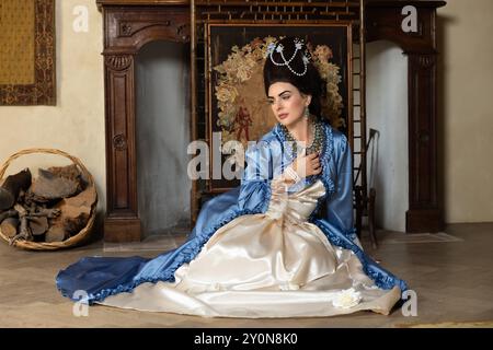 Belle jeune femme habillée dans le style rococo reine Marie Antoinette et portant une perruque authentique posant dans un intérieur de château français Banque D'Images