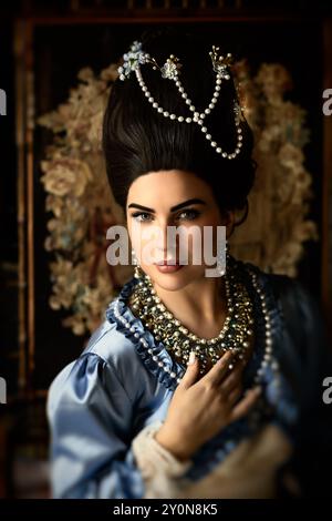 Belle jeune femme habillée dans le style rococo reine Marie Antoinette et portant une perruque authentique posant dans un intérieur de château français Banque D'Images