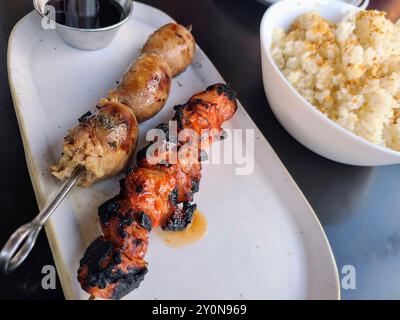 Saucisses grillées Philippines et brochettes de poulet avec gros plan sur un bol à riz Banque D'Images