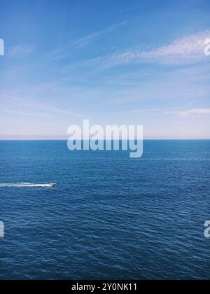 Vaste mer ouverte avec bateau rapide sous ciel bleu clair Banque D'Images
