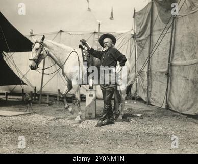 William F. 'Buffalo Bill' Cody avec cheval sur Wild West Show Backlot, vers 1895-1905 - Cody debout avec un cheval tacheté de couleur claire entre les tentes sur le backlot de son spectacle Wild West Banque D'Images