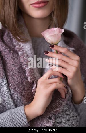 Une jeune belle femme tient une fleur d'eustoma rose dans ses mains, gros plan Banque D'Images