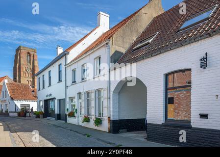 Rue pavée avec de vieilles maisons blanches et clocher de l'église notre-Dame dans le village Lissewege près de Bruges en été, Flandre occidentale, Belgique Banque D'Images