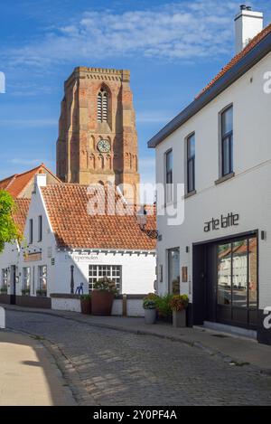 Rue pavée avec restaurant, café-bar et clocher de l'église notre-Dame au village Lissewege près de Bruges en été, Flandre occidentale, Belgique Banque D'Images