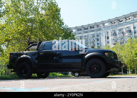 Bucarest, Roumanie - 28 juillet 2024 : camion noir Ford F-150 SVT Raptor sur un parking dans un quartier résidentiel de la ville. Vue du côté droit Banque D'Images