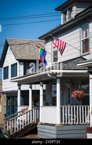Un drapeau américain et LGBTQ volent l'un à côté de l'autre sur une vieille maison. Pendleton OREGON, États-Unis. Banque D'Images