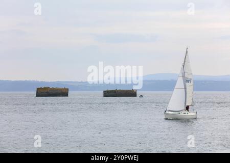 Segelboot vor den zwei von der deutschen Marine im zweiter Weltkrieg in der Bucht Rade de Brest vor der Halbinsel Plougastel-Daoulas gebauten Dalben, an denen das Schlachtschiff Bismarck anlegen sollte, hinten Halbinsel Crozon mit dem menez Ham, Departement Finistere Penn-Ar-Bed, Region Breizh, Frankreich *** là où le cuirassé Bismarck devait amarrer, derrière la péninsule de Crozon avec le menez Ham, le Finistère Penn Ar Bed part Banque D'Images