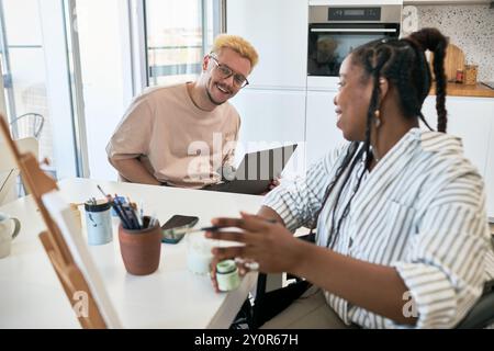 Collègues multiraciaux profitant d'une séance de brainstorming productive dans un espace de bureau moderne avec des ordinateurs portables et des fournitures dispersés sur la table, partageant des idées et des idées Banque D'Images