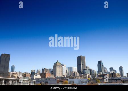 Les bâtiments emblématiques du vieux Montréal (Vieux Montréal) et les gratte-ciel d'affaires du CBD pris du port sous un ciel bleu, mettant en valeur un mélange de modernité et d'histoire Banque D'Images