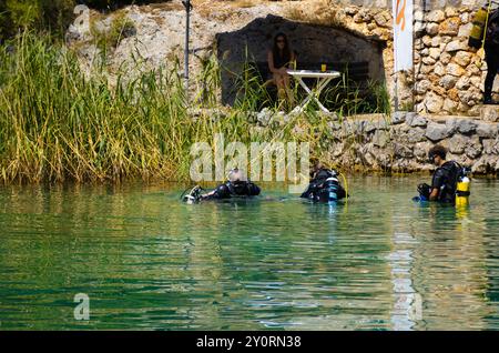 25 août 2024, Ohrid Bay of the Bones, Macédoine du Nord plongeurs en combinaisons noires de plongée sous-marine, un homme et une femme avec des bouteilles d'oxygène coulent sous le transp Banque D'Images