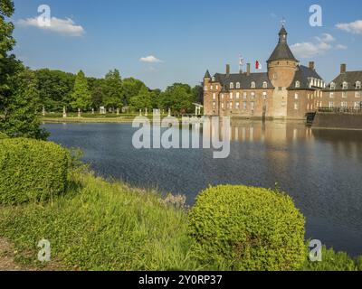 Un château historique en briques douves, des reflets dans l'étang, entouré d'un paysage verdoyant et d'un ciel bleu avec peu de nuages, Anholt, Rhénanie du Nord-Westphalie Banque D'Images