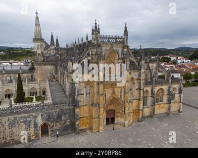 Impressionnante cathédrale gothique avec une grande entrée et des tours détaillées sous un ciel nuageux, vue aérienne, monastère, Mosteiro de Santa Maria da Vitoria, Banque D'Images