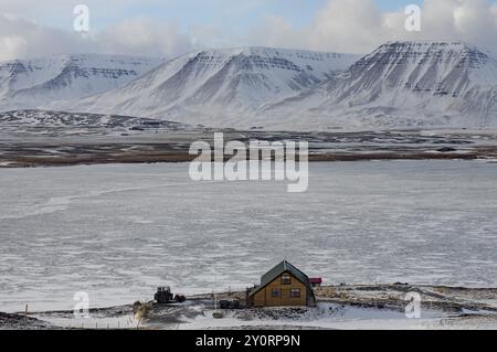 Une maison de vacances isolée dans un paysage enneigé sur un paysage montagneux impressionnant, nord de l'Islande, Islande, Europe Banque D'Images