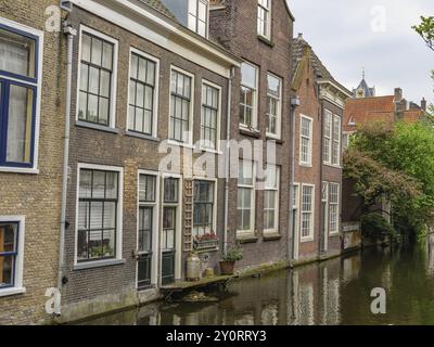 Rangée de maisons en briques le long d'un canal calme avec des détails architecturaux historiques, delft, pays-bas Banque D'Images