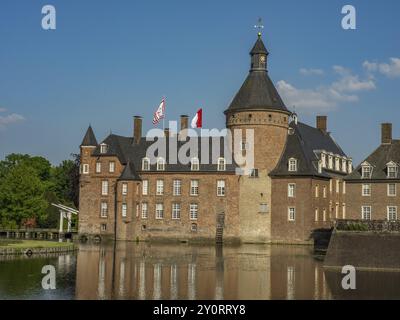 Un château impressionnant avec des tours et des drapeaux sur l'eau, reflété dans la surface lisse de l'eau, Anholt, Rhénanie du Nord-Westphalie, Allemagne, Europe Banque D'Images