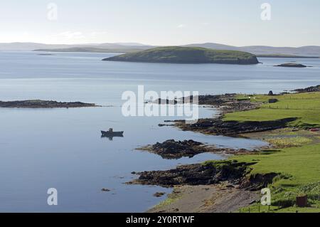 Paysage côtier paisible avec vue sur les eaux calmes, les petites îles et un bateau au loin, Scalloway, Mainland, îles Shetland, Écosse, unissez-vous Banque D'Images