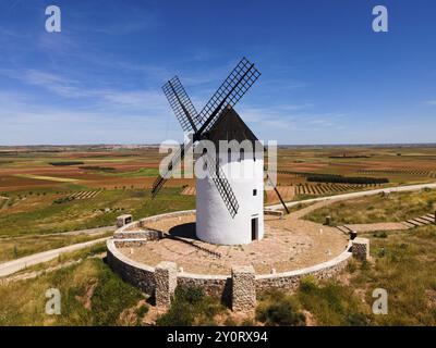 Moulin à vent blanc avec toit noir sur une colline entourée de murs de pierre et de larges champs, vue aérienne, Alcazar de San Juan, Ciudad Real, Castille-la Manche, Banque D'Images