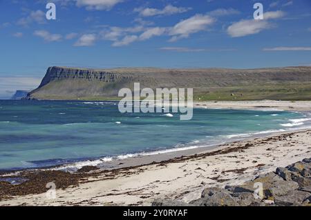 Une journée claire sur une plage de sable fin avec des vagues qui s'écrasent contre le rivage et de l'eau bleu saphir, Latrabjarg, péninsule de Vestfirðir, Islande, Europe Banque D'Images