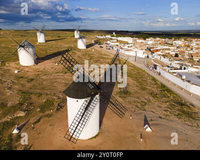 Moulins à vent dans un cadre rural par temps ensoleillé avec ciel bleu et nuages. En arrière-plan un village avec des maisons blanches et des toits rouges. Vue aérienne, vent Banque D'Images