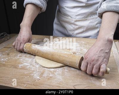 Une photo conceptuelle de rouler de la pâte sur une planche à découper à l'aide d'un rouleau à pâtisserie Banque D'Images