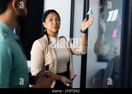 Présentation d'idées sur panneau de verre, femme discutant du projet avec un collègue dans le bureau Banque D'Images