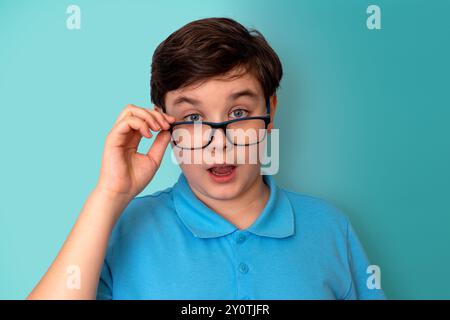 Un beau garçon drôle surpris, aux cheveux foncés, portant des lunettes et un T-shirt bleu, Banque D'Images