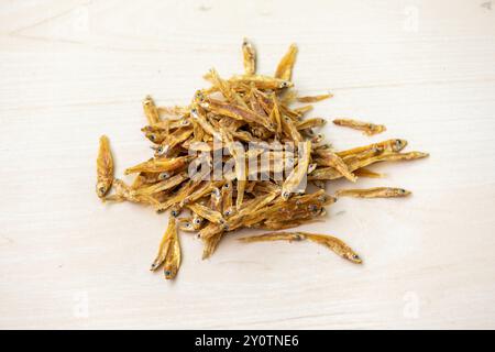 Tas de poissons anchois séchés (Corica soborna) sur fond de bois. Localement au Bangladesh, il est appelé Kachki Shutki. Banque D'Images