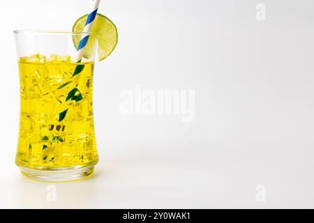 Une photo horizontale montrant une limonade jaune rafraîchissante avec beaucoup de glace et une garniture de tranche de citron. Une paille bleue ajoute à l'attrait. La boisson est posi Banque D'Images