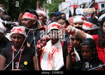 Environ 100 000 Tamouls ont marché à travers Londres aujourd'hui de Hyde Park à Temple place, appelant à la justice au Sri Lanka et à la création d'un État tamoul séparé dans ce pays. La marche a été menée par un groupe de «détenus» dans un camp de prisonniers de barbelés pour dramatiser les terribles conditions de vie des civils détenus dans les camps d'internement et exiger leur libération immédiate ainsi que l'accès total des Nations Unies aux camps. Certains portaient également des photographies de leurs proches qui ont été tués ou qui ont disparu et demandaient que le gouvernement et l'armée sri-lankais soient jugés pour crimes de guerre, ainsi que pour demander des sanctions économiques Banque D'Images